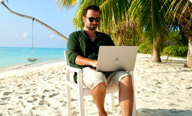 person_sitting_on_a_beach_using_a_laptop