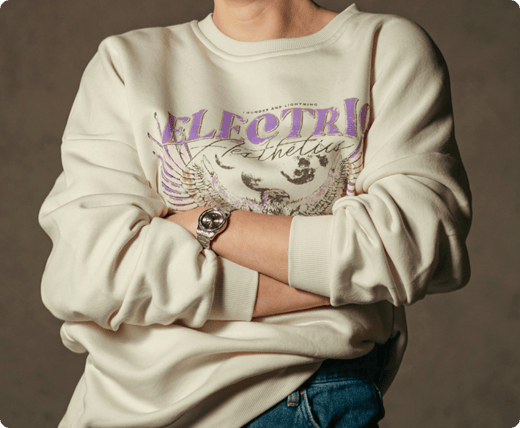 a_person_is_wearing_a_cream-colored_sweatshirt_with_a_purple_and_brown_graphic
